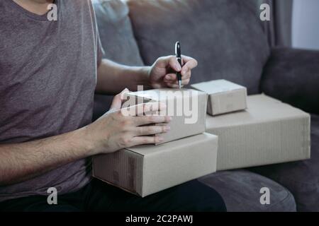 Jeune homme d'affaires asiatique mains écrire l'adresse sur boîte en carton au lieu de travail ou bureau à domicile. Banque D'Images