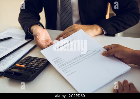 Une femme prend la poignée à l'enveloppe de démission tout en étant remise à la femme gestionnaire. Banque D'Images