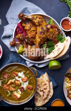 Dîner de cuisine indienne : poulet tandoori, biryani, lentille rouge curry dal avec riz naan, paneer palak et riz basmati sur fond de béton foncé Banque D'Images