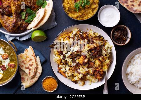 Dîner de cuisine indienne : poulet tandoori, biryani, lentille rouge curry dal avec riz naan, paneer palak et riz basmati sur fond de béton foncé Banque D'Images