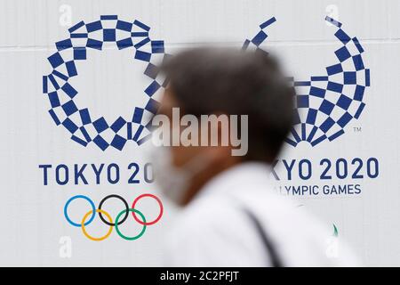 Tokyo, Japon. 18 juin 2020. Un homme portant un masque passe devant les logos des Jeux olympiques et paralympiques de Tokyo en 2020 dans le centre-ville de Tokyo. Les médias japonais ont indiqué qu'un membre du conseil exécutif de Tokyo 2020 a déclaré qu'il fallait demander un autre retard si les jeux ne peuvent pas avoir lieu l'année prochaine en raison de la pandémie du coronavirus. Le Comité International Olympique et le Comité d'organisation local ont déclaré que les Jeux seront annulés s'ils ne peuvent pas avoir lieu le 2021 juillet prochain. Credit: Rodrigo Reyes Marin/ZUMA Wire/Alay Live News Banque D'Images