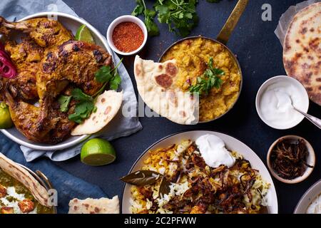 Dîner de cuisine indienne : poulet tandoori, biryani, lentille rouge curry dal avec riz naan, paneer palak et riz basmati sur fond de béton foncé Banque D'Images