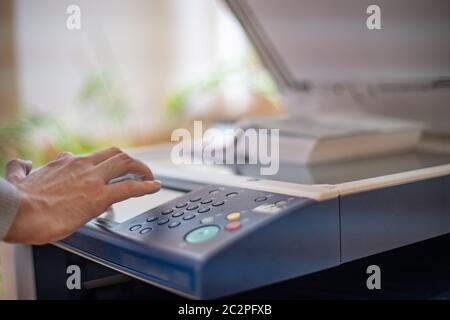 main d'homme utilisant la machine de copie d'impression dans la bibliothèque Banque D'Images