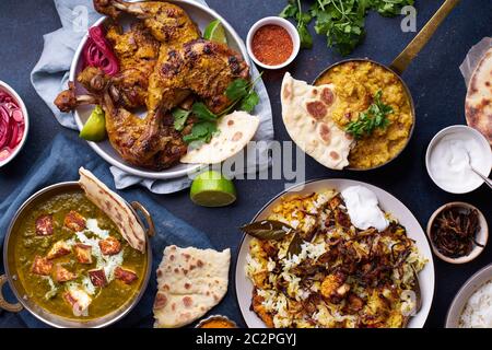 Dîner de cuisine indienne : poulet tandoori, biryani, lentille rouge curry dal avec riz naan, paneer palak et riz basmati. Vue de dessus sur le fond en béton foncé Banque D'Images