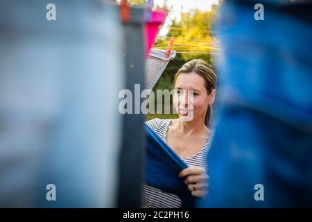 Jeune femme en mettant une corde à linge dans son jardin, en prenant bien soin de sa famille sur une base quotidienne Banque D'Images