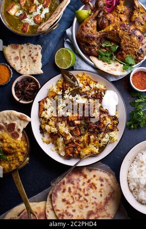 Dîner de cuisine indienne : poulet tandoori, biryani, lentille rouge curry dal avec riz naan, paneer palak et riz basmati. Vue de dessus sur le fond en béton foncé Banque D'Images