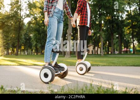 Jeune couple riding sur le gyroscope conseil en parc d'été au coucher du soleil. Loisirs de plein air avec gyroboard électrique. Transport avec la technologie de l'équilibre, de l'électricité Banque D'Images