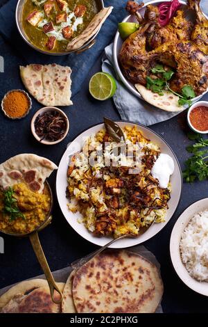 Dîner de cuisine indienne : poulet tandoori, biryani, lentille rouge curry dal avec riz naan, paneer palak et riz basmati. Vue de dessus sur le fond en béton foncé Banque D'Images