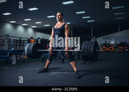 La préparation d'un powerlifter mâle deadlift barbell dans une salle de sport. Entraînement d'haltérophilie, musculation, athlète travaille avec des poids en sport club Banque D'Images