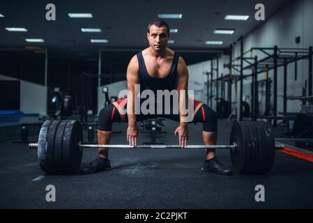 La préparation d'un powerlifter mâle deadlift barbell dans une salle de sport. Entraînement d'haltérophilie, musculation, athlète travaille avec des poids en sport club Banque D'Images