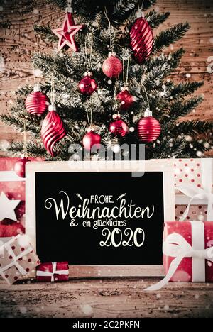 Calligraphie allemand Frohe Weihnachten und ein 2020 Glueckliches veut dire Joyeux Noël et une Bonne 2020. Arbre de Noël avec des cadeaux, un ornement de Red Ball Banque D'Images
