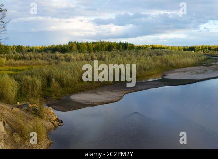 Coucher de soleil lumineux avec réflexion dans les nuages d'eau une petite rivière Kempendyay dans Yakutia au large d'une falaise et forêts d'épicéa dans le nord sauvage de la piste et le Th Banque D'Images