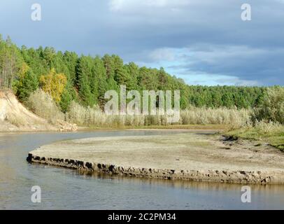 Érosion érosion la rive sablonneuse d'une petite rivière Yakut du Nord dans la taïga sauvage du Nord dans une forêt pittoresque d'épinette. Banque D'Images