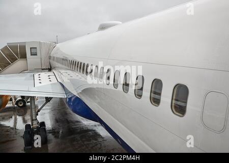 Détails du fuselage d'un avion passager à un aéroport avec passerelle à jet connectée pour l'embarquement Banque D'Images