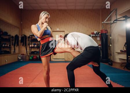 Personne de sexe féminin fait un coup de pied dans l'aine, légitime défense d'entraînement avec entraîneur personnel, masculin de sport intérieur sur l'arrière-plan. Femme sur la formation, l'auto-défense Banque D'Images