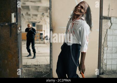 Homme aux armes à feu lutte avec zombie mort-mort, cauchemar dans l'usine abandonnée. Horreur en ville, craies effrayantes, apocalypse doomsday, monstre sanglant du mal Banque D'Images