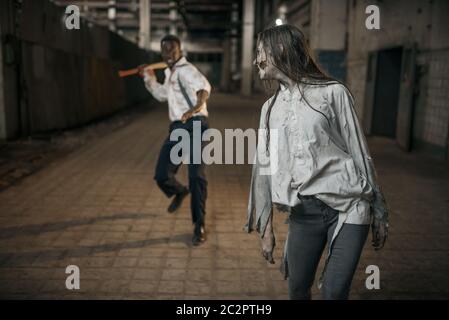 Un homme avec une hache a attaqué des femmes zombies dans une usine abandonnée, un endroit effrayant. Horreur en ville, craies effrayantes, apocalypse doomsday, monstres sanglants du mal Banque D'Images