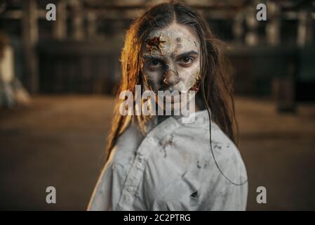 Femme zombie marchant dans une usine abandonnée, endroit effrayant. Horreur en ville, attaque de craies effrayantes, apocalypse doomsday, monstre sanglant du mal Banque D'Images