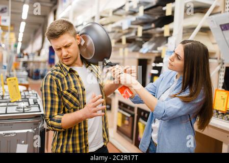 Jeune couple avec poêle dans le magasin d'électronique. Homme et femme achetant des appareils électriques domestiques sur le marché Banque D'Images