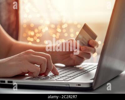 Cristmas shopping en ligne soncept. Gros plan les mains de la femme tenant la carte de crédit et en saisissant les informations de carte à l'aide du clavier d'ordinateur portable pour les achats en ligne Banque D'Images