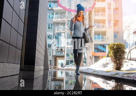 Femme marchant dans les flaques de la ville avant le printemps Banque D'Images