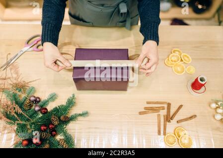 Vendeur femelle décore boîte-cadeau avec du papier d'emballage et ruban d'or, de la décoration. Femme wraps présent sur la table, le décor intérieur Banque D'Images