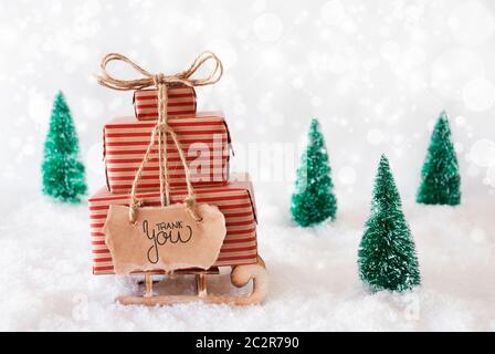 Traîneau avec cadeau de Noël et de l'étiquette avec la calligraphie anglaise Je vous remercie. Arbre de Noël avec de la neige et gris fond mousseux Banque D'Images