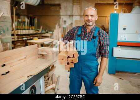 Carpenter détient une pile de poutres en bois, travail du bois, industrie du bois, menuiserie. Transformation du bois sur une usine de meubles, production de produits natura Banque D'Images