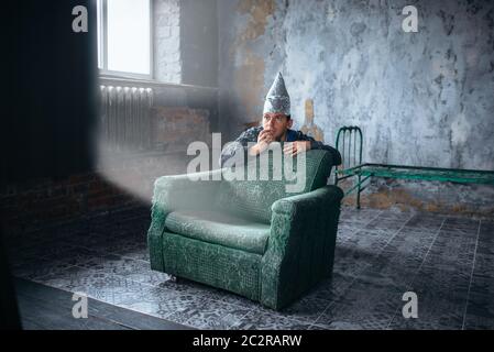 Homme peur en aluminium bouchon regarder la TV, protection de l'esprit, concept de paranoïa. OVNI, théorie du complot, phobie de la télépathie Banque D'Images