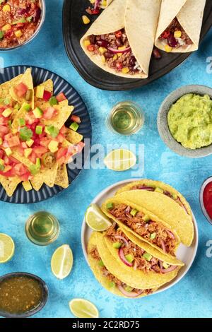 Foodflatlay mexicain, les frais généraux tourné sur fond bleu turquoise. Nachos, tequila avec limes, coquilles à tacos, burritos, guacamole Banque D'Images
