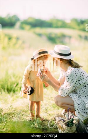 Une mère nourrit sa fille avec un croissant tout en marchant dans le parc. Banque D'Images