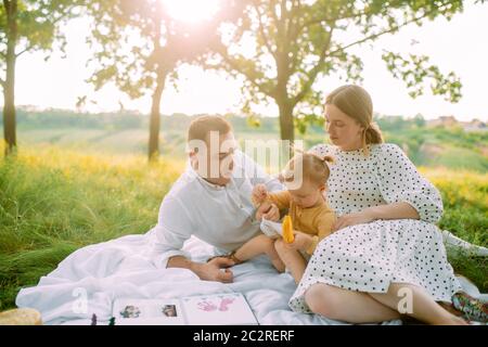 La famille avec sa petite fille se repose pendant le pique-nique dans le parc. Banque D'Images