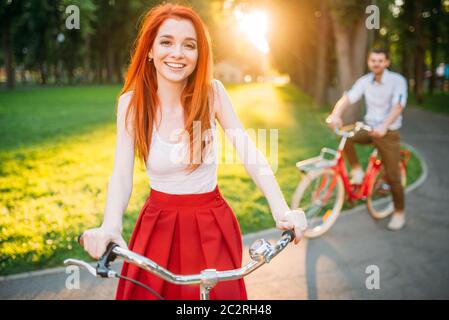 Heureux couple amour rétro se déplace sur des vélos en été Parc sur le coucher du soleil. Date romantique Banque D'Images