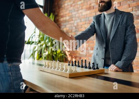 Les joueurs d'échecs se secouent la main avant le match. Deux hommes de chessplayers commencent la bataille intellectuelle à l'intérieur. Banque D'Images