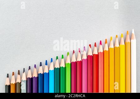un ensemble de crayons colorés alignés dans une rangée de plus en plus haut de la nuit à la lumière Banque D'Images
