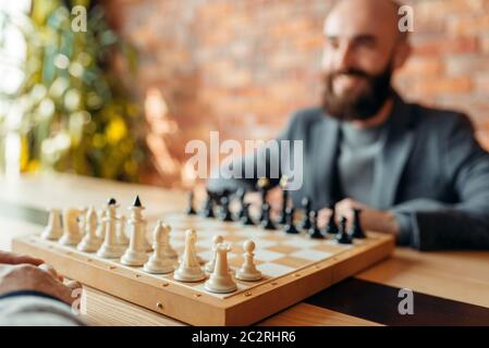 Les joueurs d'échecs de commencer à jouer, se concentrer à bord avec les chiffres. Deux chessplayers commencer le tournoi intellectuelle à l'intérieur. Sur l'Échiquier, table en bois Banque D'Images