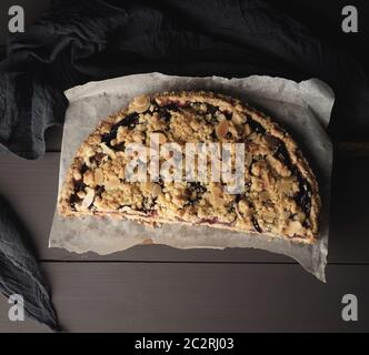 La moitié crumble Tarte aux prunes sur une planche à découper en bois brun, vue du dessus Banque D'Images