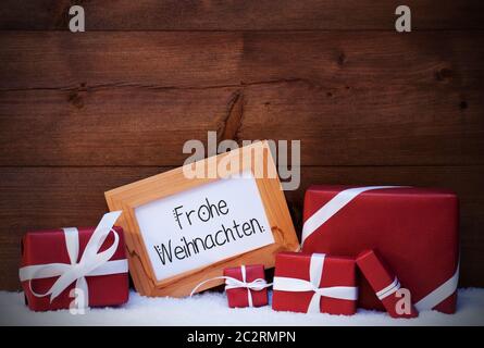 Châssis avec calligraphie allemand Frohe Weihnachten signifie joyeux Noël. Cadeaux de Noël rouge et d'aujourd'hui. Fond de bois avec de la neige Banque D'Images
