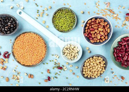 Légumineuses, tiré du dessus sur un fond bleu. Des légumineuses vibrantes, dont des haricots colorés, des lentilles, des pois chiches, une composi à plat Banque D'Images