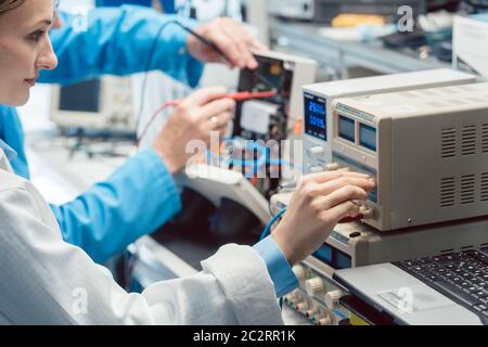 Deux ingénieurs en électronique sur le banc d'essai en laboratoire mesurant un nouveau produit pour la conformité CEM Banque D'Images