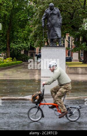 Westminster, Londres, Royaume-Uni. 18 juin 2020. La statue de Winston Churchill à l'extérieur du Palais de Westminster a été découverte à la suite des mesures prises pour empêcher qu'elle ne soit encore vandalisée pendant les manifestations de Black Lives Matter. Le président français Emmanuel Macron se rend à Londres pour le 80e anniversaire du discours de « l'appel » de Charles de Gaulle, qui est considéré comme l'origine de la résistance française à l'occupation allemande pendant la Seconde Guerre mondiale, de sorte que la statue a été révélée. Faire du vélo pour travailler un matin pluvieux Banque D'Images