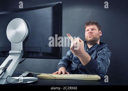 Fat angry man sitting at desk à l'écran à surveiller Banque D'Images