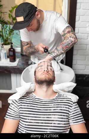 Le jeune homme a lavé ses cheveux dans le magasin de coiffure, barber lave la tête de son client Banque D'Images