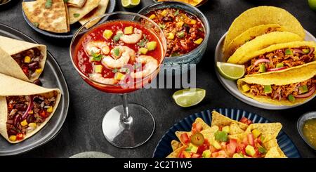 La nourriture mexicaine panorama sur un fond noir. Un cocktail de crevettes, chili con carne, tacos et autres plats Banque D'Images