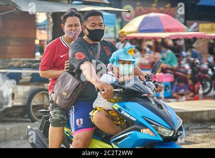 Une famille thaïlandaise sur une moto portant des masques protecteurs. Banque D'Images