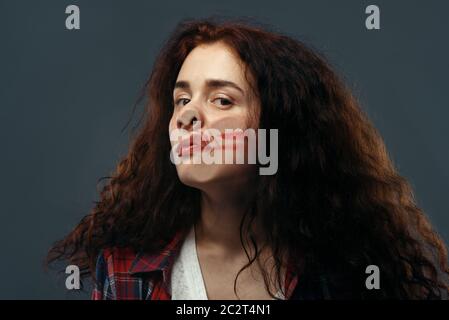 Le visage de la jeune femme est écrasé sur du verre transparent, une fille avec un rouge à lèvres taché. Femme debout à la vitrine avec un regard inconfortable, humour, Banque D'Images