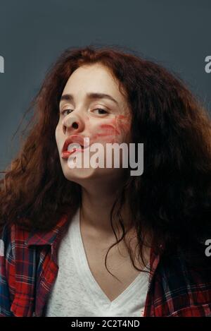 Le visage de la jeune femme est écrasé sur du verre transparent, une fille avec un rouge à lèvres taché. Femme debout à la vitrine avec un regard inconfortable, humour, Banque D'Images