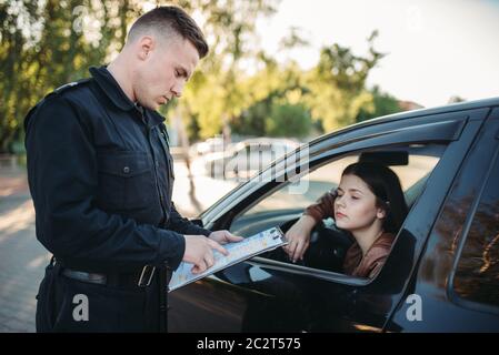 Policier en uniforme écrit une amende à la pilote. La protection de la loi, le trafic automobile, de l'inspecteur du travail de contrôle de la sécurité Banque D'Images