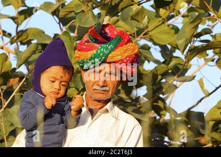 Le grand-père indien a attaché le turban dans le jardin avec le petit-fils plus jeune Banque D'Images