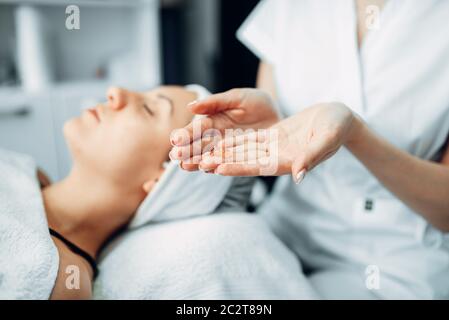 Avec de la Crème mains coiffeur contre patiente, cosmétologie clinique. Soin du visage, rajeunissement procédure en spa salon Banque D'Images